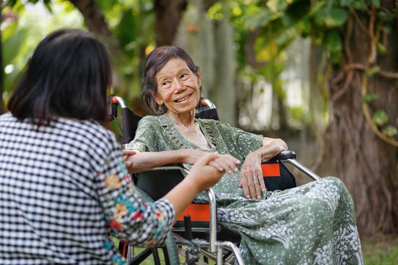 Older adult in wheelchair with caregiver