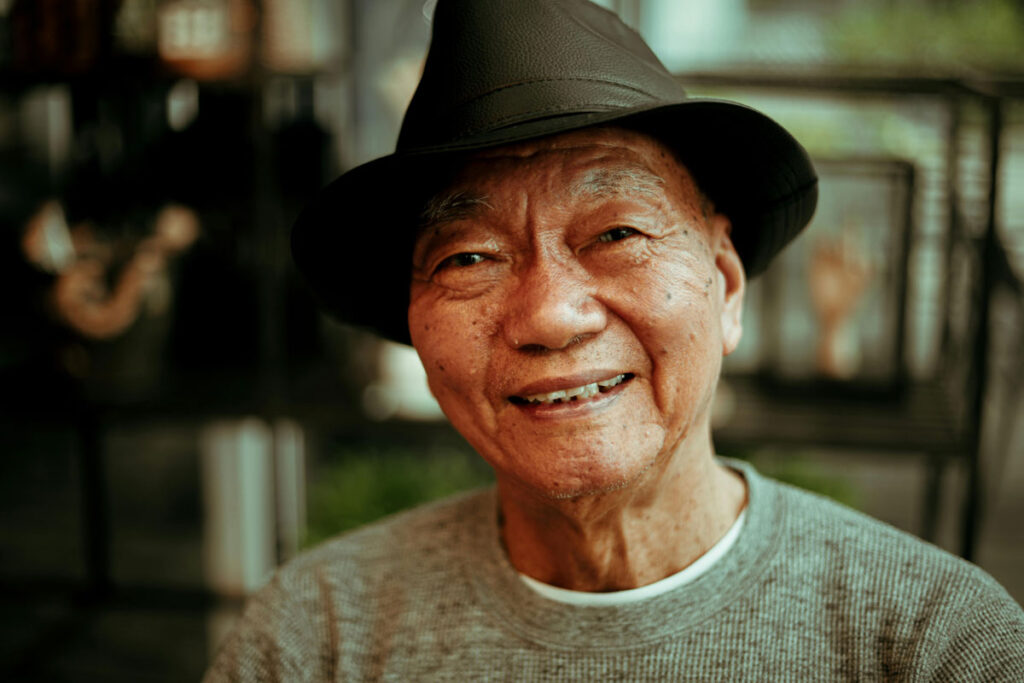 Asian elderly man looking into the camera, smiling.